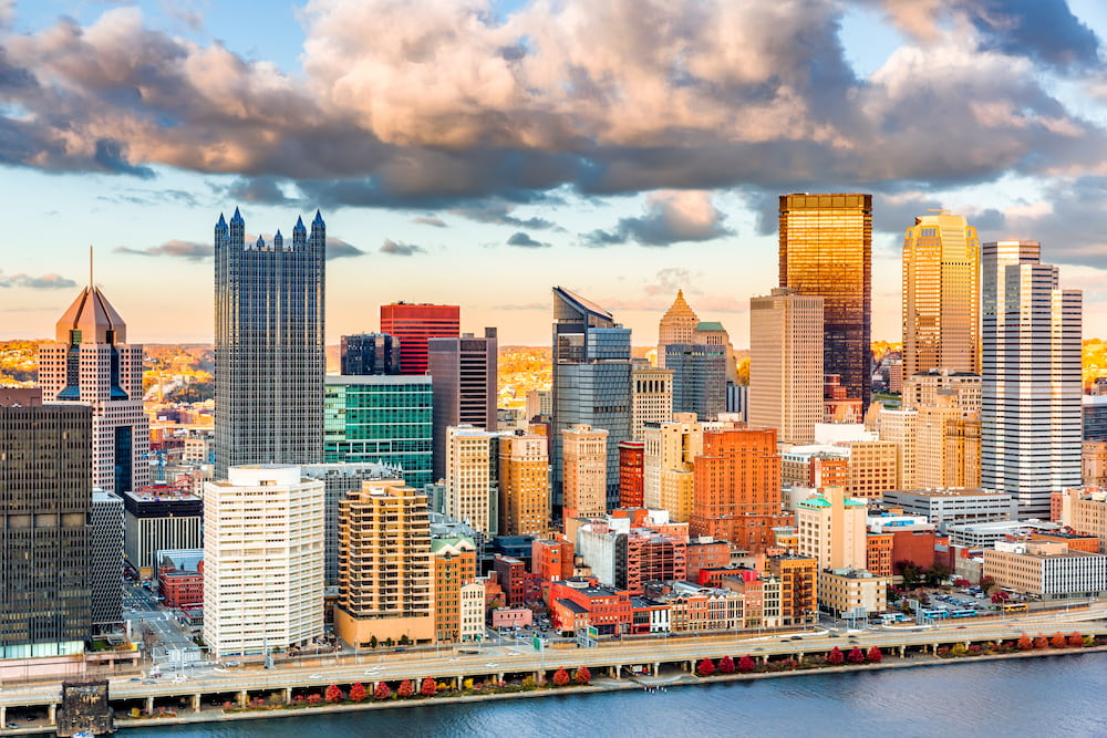 Pittsburgh downtown under a warm sunset light, viewed from Grandview Overlook across Monongahela River